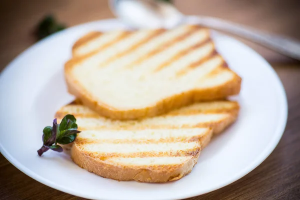 Жареный тост в тарелке на деревянном столе — стоковое фото