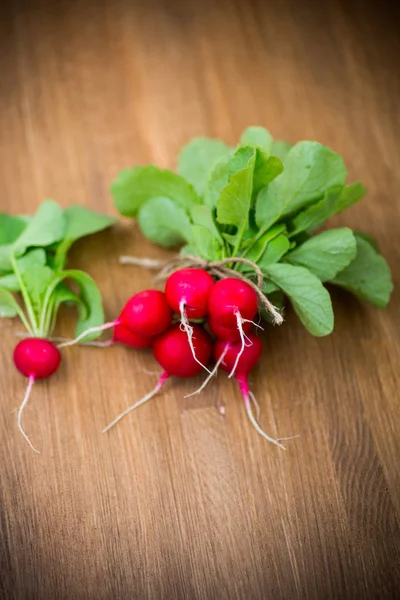 Świeże organiczne czerwone rzodkiewki na drewnianym stole — Zdjęcie stockowe