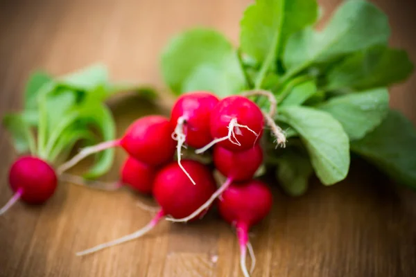 Färska organiska röd rädisor på ett trä bord — Stockfoto