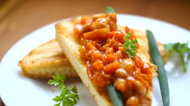 Смажені хлібні тости з тушкованими бобами та овочами в тарілці — стокове відео
