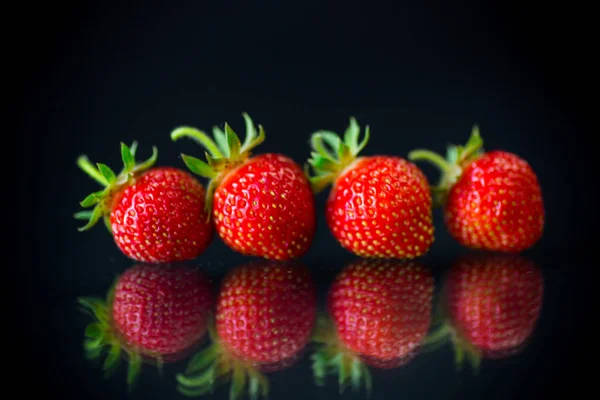 Reife rote Erdbeeren auf schwarzem Hintergrund — Stockfoto