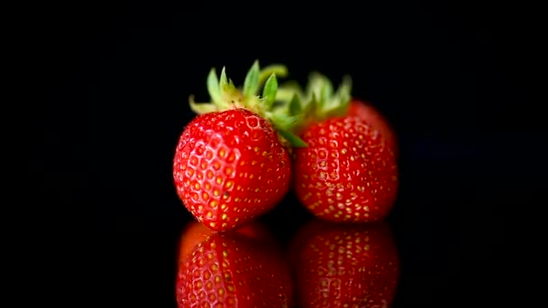 Fresas rojas maduras sobre un fondo negro — Vídeo de stock
