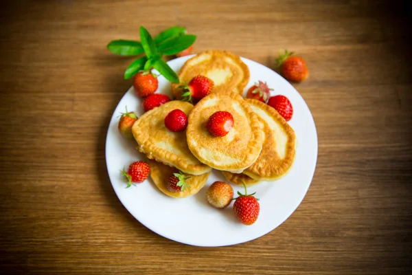Fried sweet pancakes with ripe strawberries in a plate — Stock Photo, Image