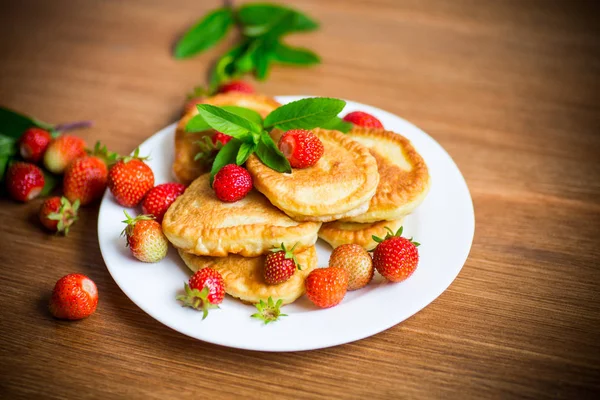 Gebakken zoete pannenkoeken met rijpe aardbeien in een bord — Stockfoto
