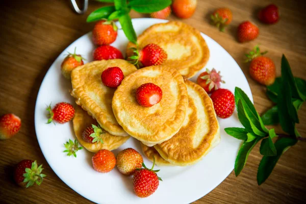 Gebratene süße Pfannkuchen mit reifen Erdbeeren in einem Teller lizenzfreie Stockfotos
