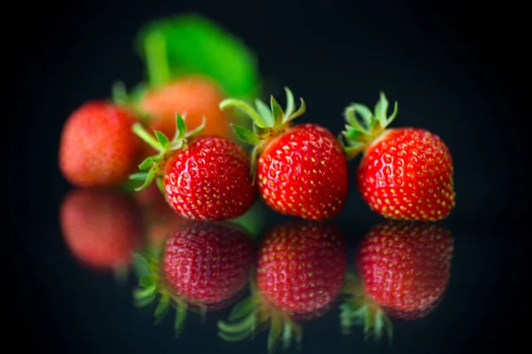 Fresas rojas maduras sobre un fondo negro —  Fotos de Stock