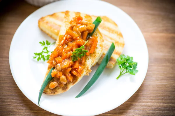 Fried bread toasts with stewed beans and vegetables in a plate — Stock Photo, Image