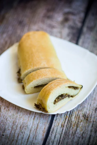 Baked yeast dough roll with fried mushrooms in a plate — Stock Photo, Image