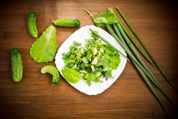 Salada fresca de pepinos e verdes em uma chapa em uma madeira — Fotografia de Stock
