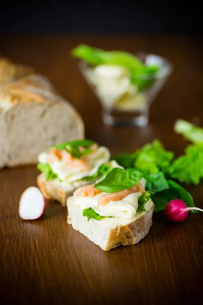 Sandwich met kaas, salade blaadjes en rode vis op een houten — Stockfoto