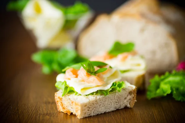 Sanduíche com queijo, folhas de salada e peixe vermelho em uma madeira — Fotografia de Stock
