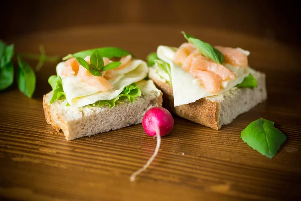 Sandwich met kaas, salade blaadjes en rode vis op een houten — Stockfoto