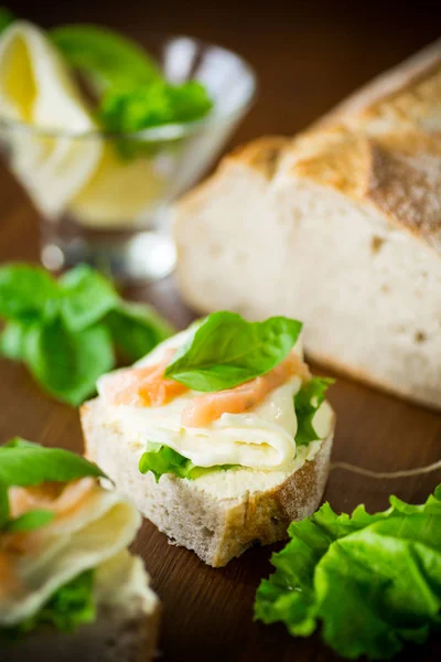 Sándwich con queso, hojas de ensalada y pescado rojo sobre una madera — Foto de Stock