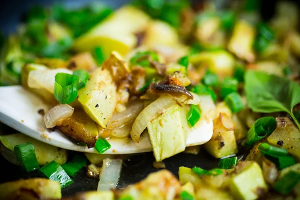 Zucchini fried with onions and herbs in a pan on a wooden table — Stock Photo, Image