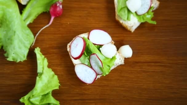 Sándwich con queso, lechuga y rábano rojo sobre una madera — Vídeo de stock