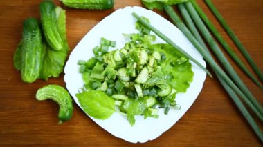 bir tahta üzerinde bir tabak salatalık ve Yeşiller taze salata