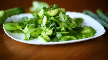 bir tahta üzerinde bir tabak salatalık ve Yeşiller taze salata