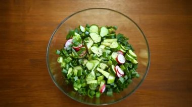 bir tahta üzerinde bir tabak salatalık ve Yeşiller taze salata
