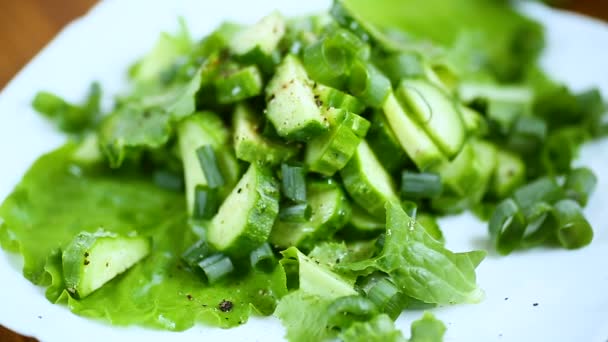 Salade fraîche de concombres et de légumes dans une assiette sur un bois — Video