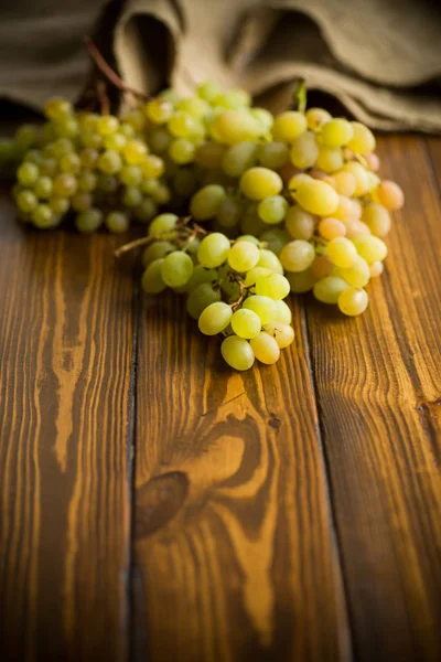 Bos van groene druiven op een donkere houten tafel — Stockfoto