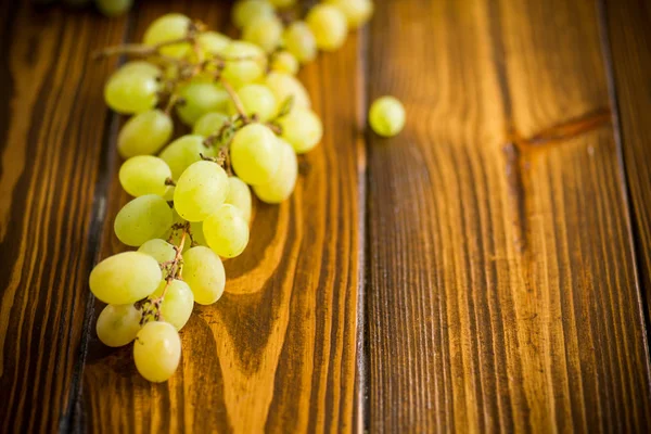 Bos van groene druiven op een donkere houten tafel — Stockfoto