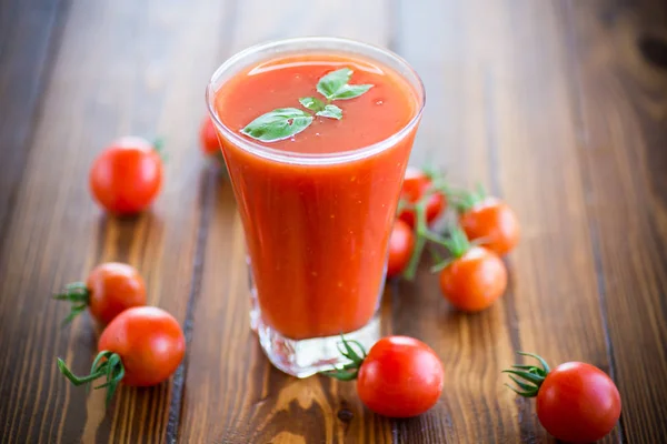 Suco de tomate caseiro em um copo e tomates frescos — Fotografia de Stock