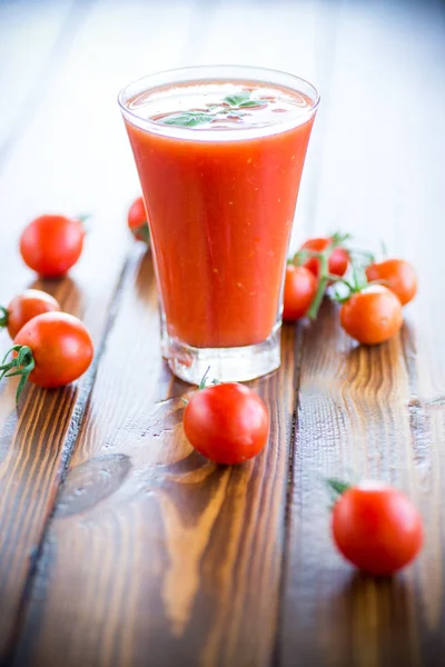 Suco de tomate caseiro em um copo e tomates frescos — Fotografia de Stock