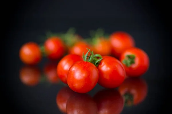 Tomates cereja pequenos vermelhos maduros em um preto — Fotografia de Stock