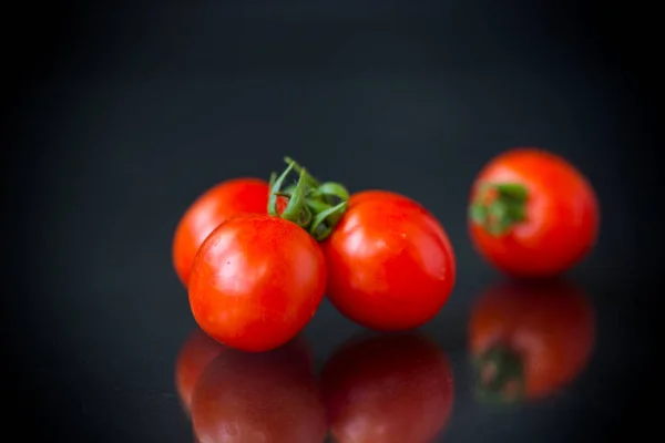 Ripe red small cherry tomatoes on a black — Stock Photo, Image