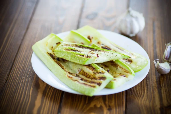Grilled zucchini with onions in a plate, on a table. — Stock Photo, Image