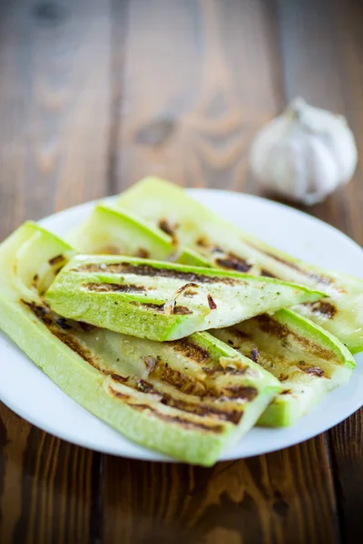 Grilled zucchini with onions in a plate, on a table. — Stock Photo, Image