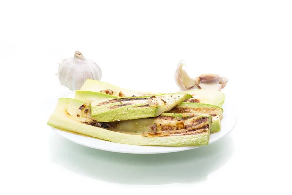 Zucchine grigliate con cipolle in un piatto, isolate su bianco — Foto Stock