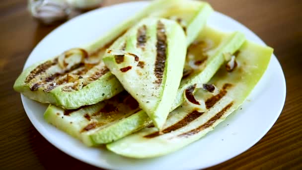 Zucchine grigliate con cipolle in un piatto, su un tavolo . — Video Stock