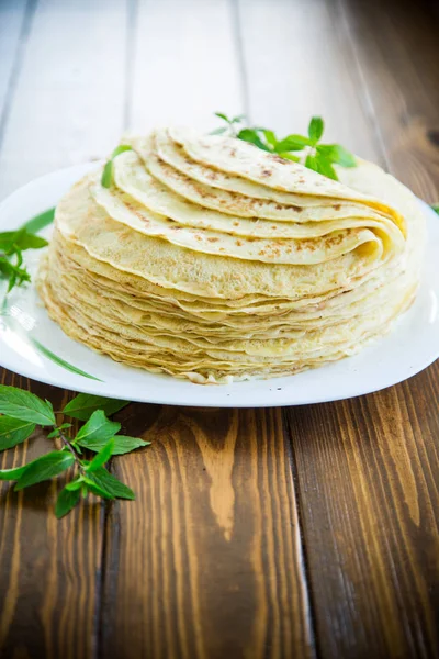 Många stekta tunna pannkakor i en tallrik, på ett bord. — Stockfoto