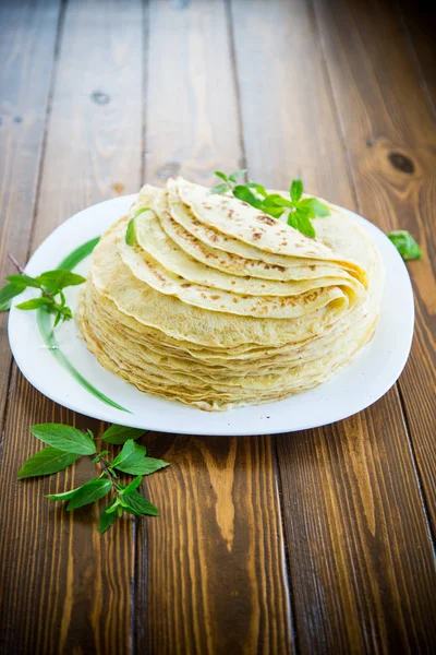 Muchos panqueques fritos delgados en un plato, sobre una mesa . — Foto de Stock