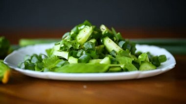 bir tahta üzerinde bir tabak salatalık ve Yeşiller taze salata