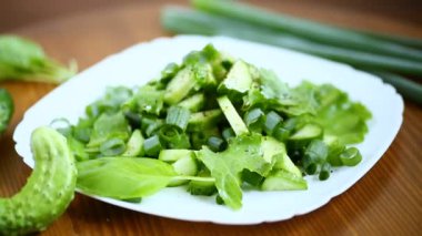 bir tahta üzerinde bir tabak salatalık ve Yeşiller taze salata