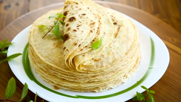 De nombreuses crêpes fines frites dans une assiette, sur fond blanc . — Video