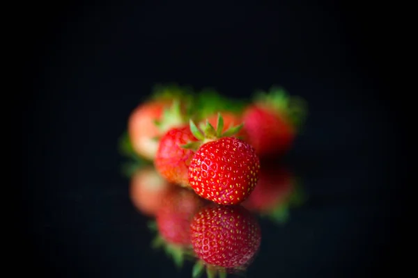 Fresas rojas maduras sobre un fondo negro —  Fotos de Stock