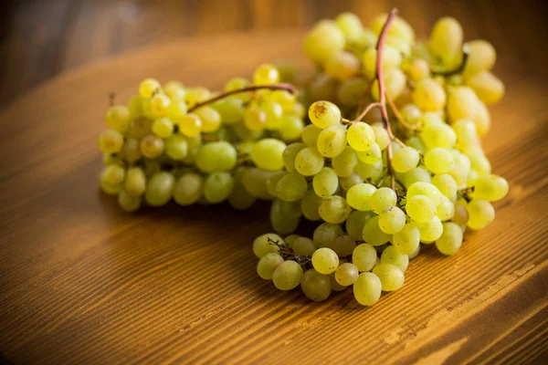 koyu ahşap bir masa üzerinde yeşil üzüm demet