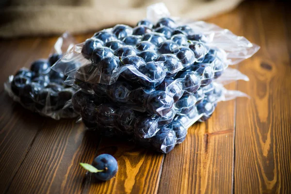 Prune mûre dans un sac à vide sur une table en bois — Photo