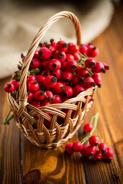 Reife rote Heckenrose in einem Korb auf einem hölzernen — Stockfoto