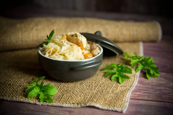 Kokt ris med grønnsaker og kjøtt i en keramikkskål på et trebord – stockfoto