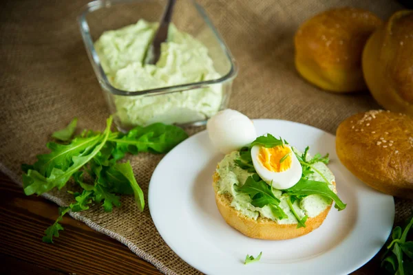 Zelfgebakken broodje met kaaspasta, verse arugula en gekookt ei in een bord — Stockfoto