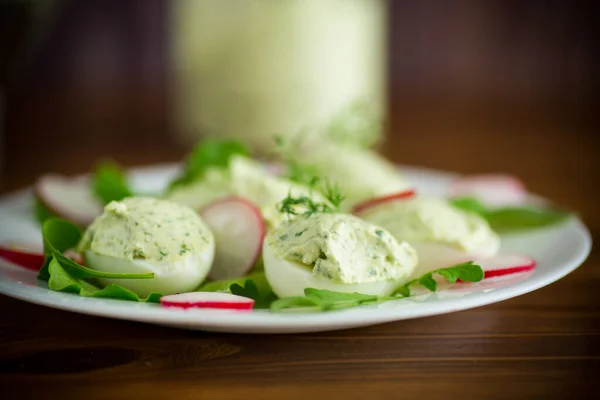 Вареные фаршированные яйца с зеленым сыром с листьями рукколы и редькой — стоковое фото