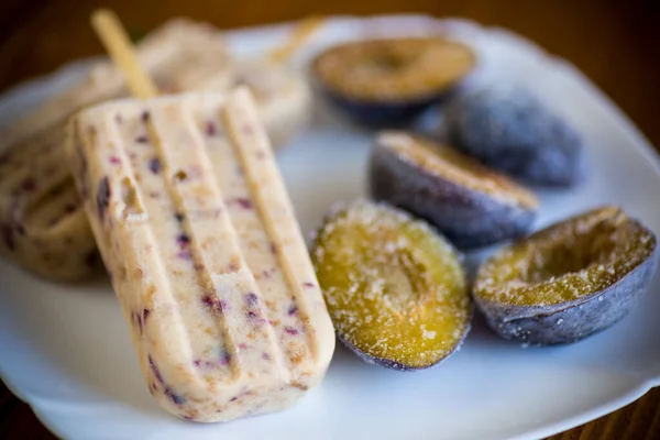 Helado casero dulce de ciruela en un palo con rebanadas de ciruela en el interior, en un plato —  Fotos de Stock