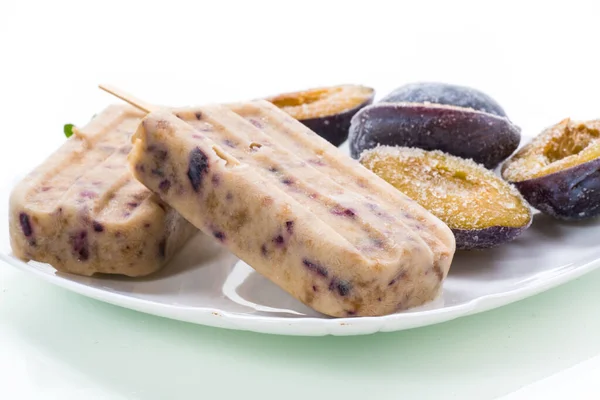 Švestková sladká domácí zmrzlina na klacku s plátky švestky uvnitř, na talíři — Stock fotografie