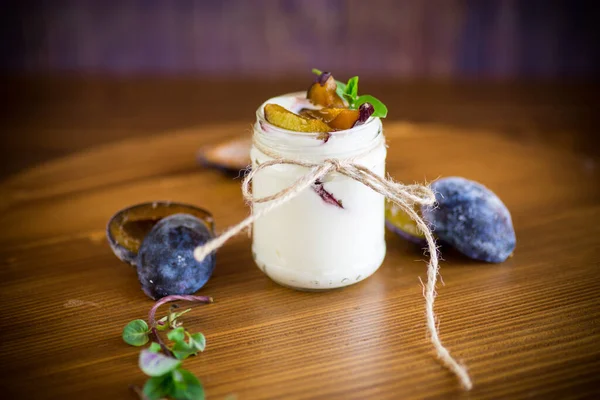 Домашний сладкий йогурт с ломтиками спелых слив в стакане — стоковое фото