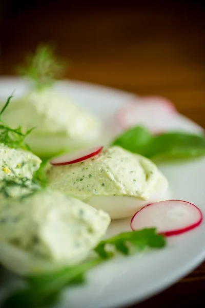 Boiled stuffed eggs with green cheese filling with arugula leaves and radish Royalty Free Stock Photos