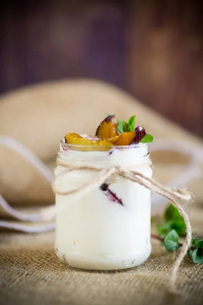 Домашній солодкий йогурт зі скибочками стиглих слив у склянці Стокове Зображення